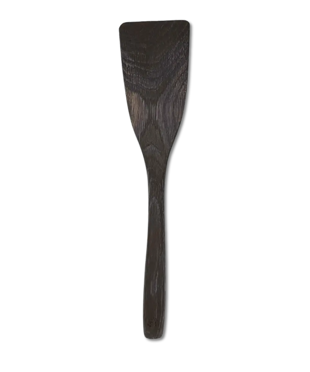 Hand-carved long wooden kitchen spatula made from smoked oak, lying flat on a neutral background.